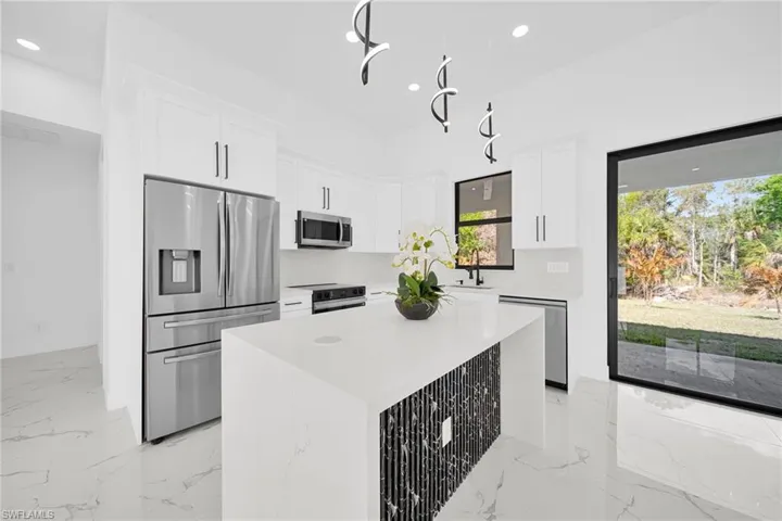 Kitchen featuring stainless steel appliances, a center island, white cabinetry, light stone countertops, and recessed lighting