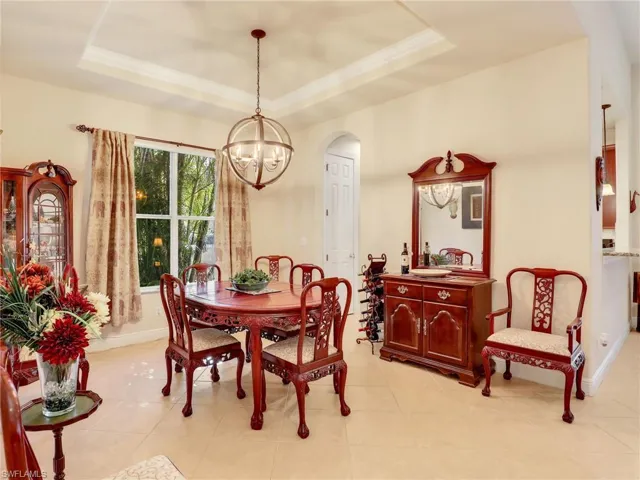 Dining area with ornamental molding, a raised ceiling, and a chandelier