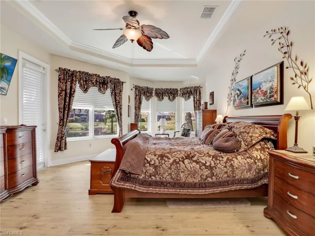 Bedroom featuring a raised ceiling, crown molding, ceiling fan, and light hardwood / wood-style floors