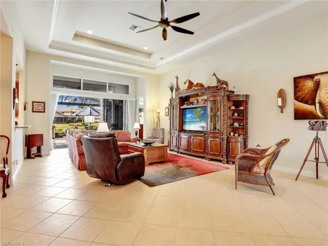 Living room with ceiling fan, a tray ceiling, and light tile patterned floors