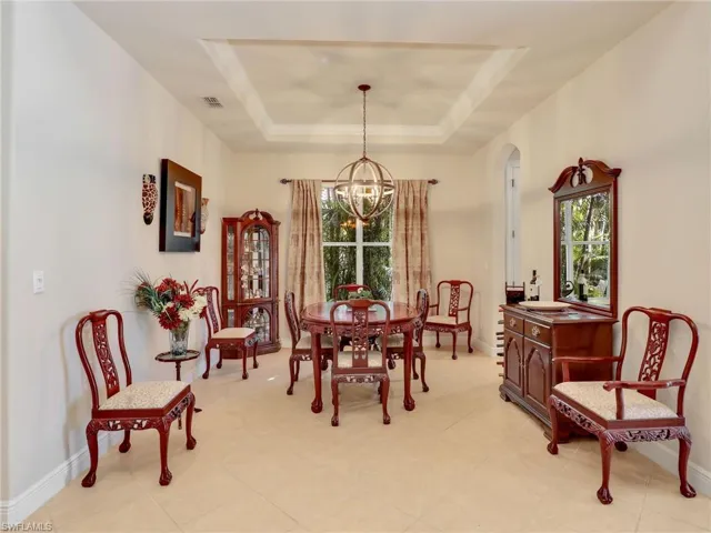 Dining room featuring an inviting chandelier, a healthy amount of sunlight, and a tray ceiling