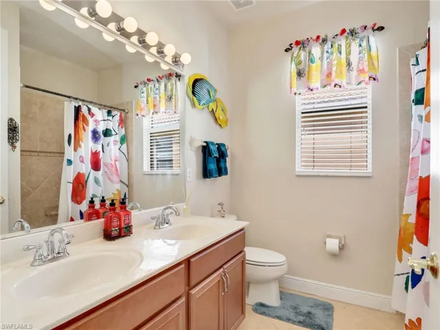 Bathroom with tile patterned floors, toilet, curtained shower, and vanity