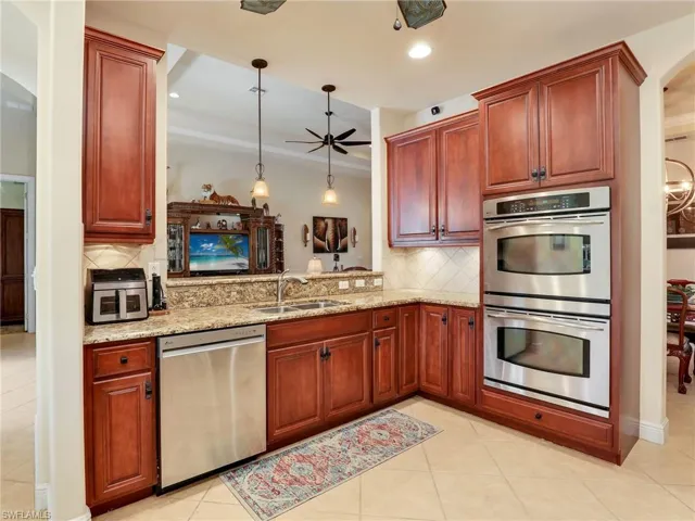 Kitchen featuring appliances with stainless steel finishes, decorative light fixtures, sink, kitchen peninsula, and light stone countertops