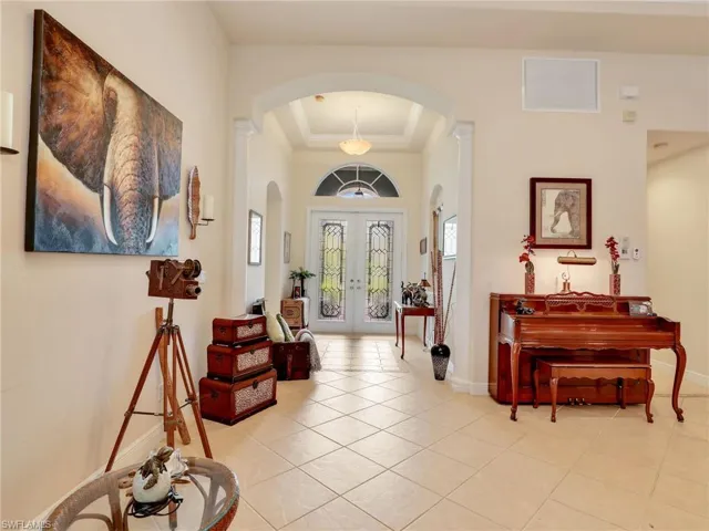 Tiled entrance foyer featuring a tray ceiling, ornamental molding, and french doors