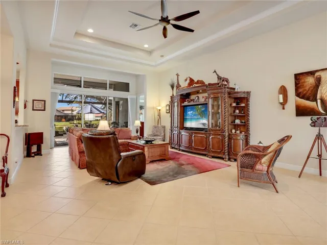 Tiled living room with a high ceiling, ceiling fan, and a tray ceiling