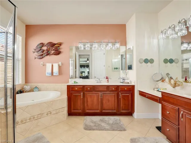 Bathroom featuring a relaxing tiled tub, tile patterned floors, and vanity