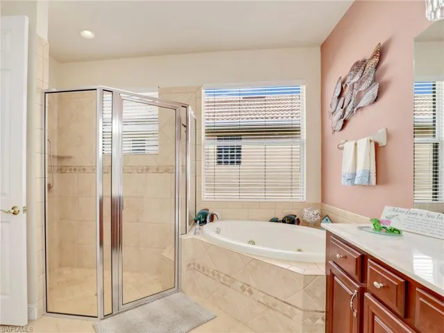 Bathroom featuring tile patterned floors, vanity, and separate shower and tub