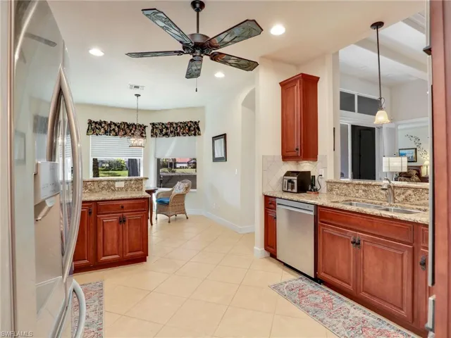 Kitchen with decorative light fixtures, sink, backsplash, stainless steel appliances, and light stone countertops