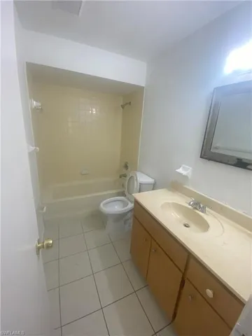 Full bath with shower / tub combination, vanity, and light tile patterned floors