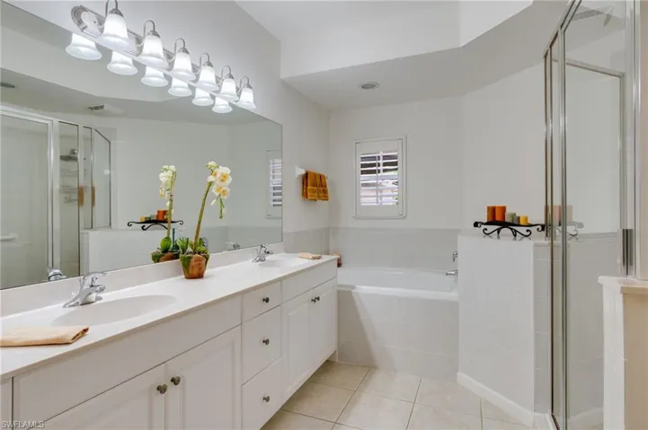 Full bath with a stall shower, double vanity, a garden tub, and light tile patterned flooring