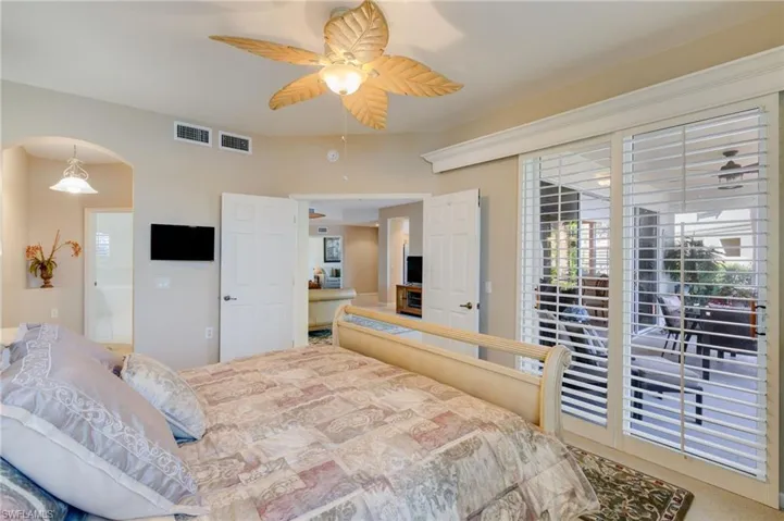Carpeted bedroom with access to outside, arched walkways, and a ceiling fan