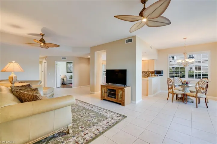 Living room featuring ceiling fan, light tile patterned floors, and a chandelier