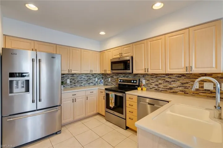 Kitchen featuring stainless steel appliances, light tile patterned flooring, light wood finish cabinets, backsplash, and recessed lighting