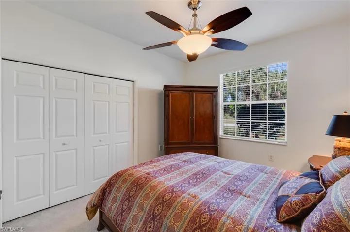 Carpeted bedroom featuring ceiling fan and a closet