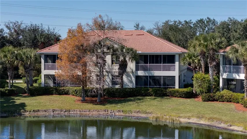 Back of house featuring a tile roof, a sunroom, a yard, and stucco siding