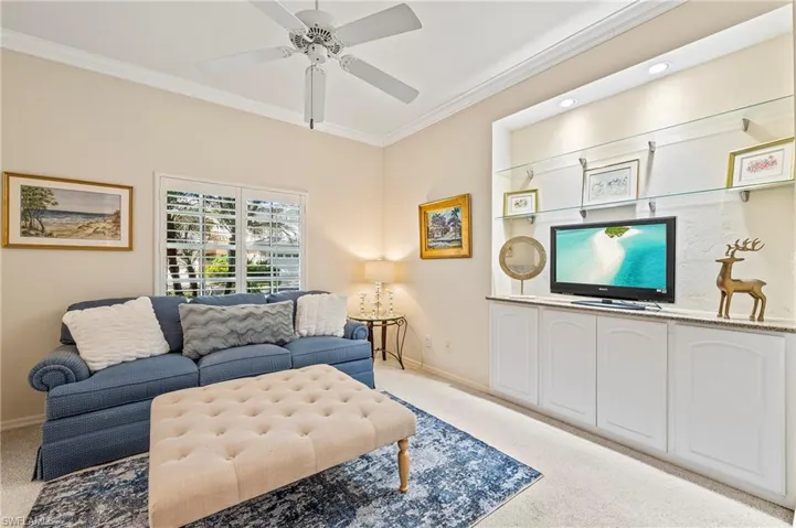 Living room with light carpet, ceiling fan, and crown molding