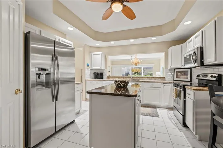 Kitchen featuring white cabinets, a kitchen island, backsplash, and appliances with stainless steel finishes