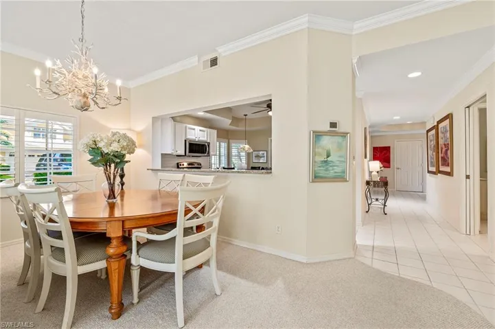 Dining room featuring crown molding, light colored carpet, and ceiling fan with notable chandelier