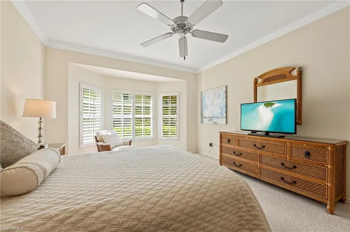 Carpeted bedroom featuring ceiling fan and ornamental molding