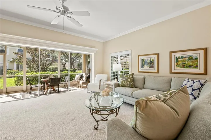Carpeted living room with crown molding and ceiling fan