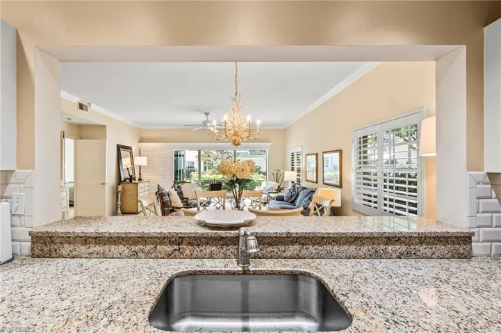 Kitchen with a wealth of natural light, ornamental molding, sink, and light stone countertops