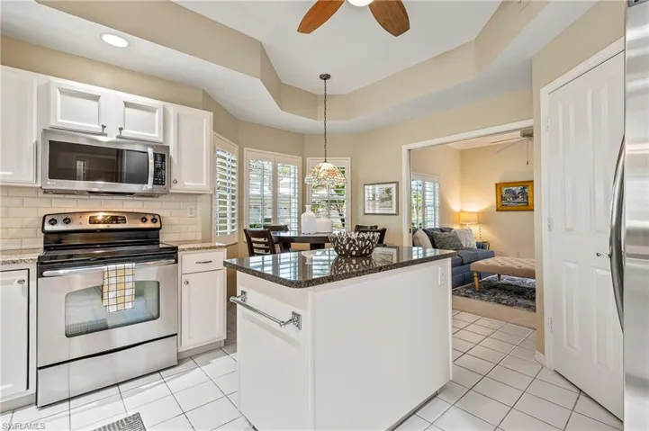 Kitchen featuring dark stone countertops, white cabinetry, plenty of natural light, and appliances with stainless steel finishes