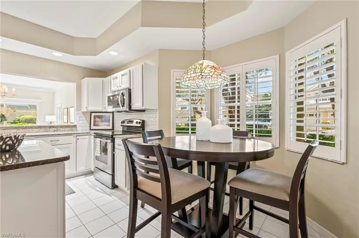 Dining area with light tile patterned floors, a wealth of natural light, and a tray ceiling