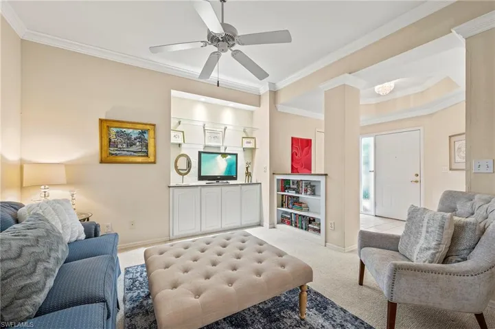 Living room with light colored carpet, decorative columns, ornamental molding, and ceiling fan