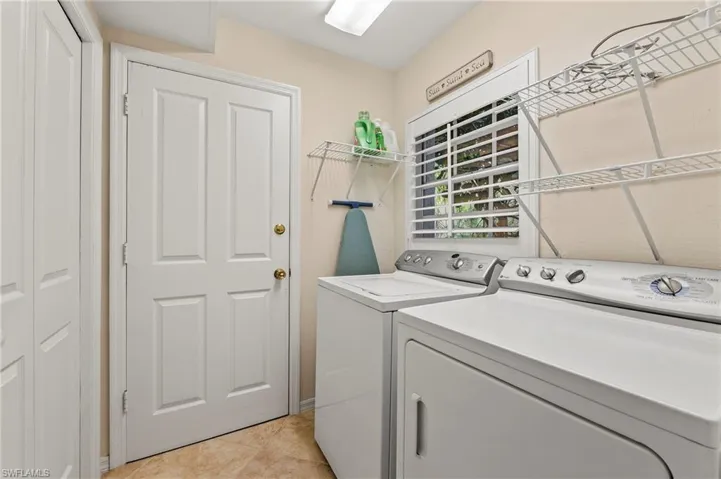 Laundry area with washing machine and clothes dryer and light tile patterned floors