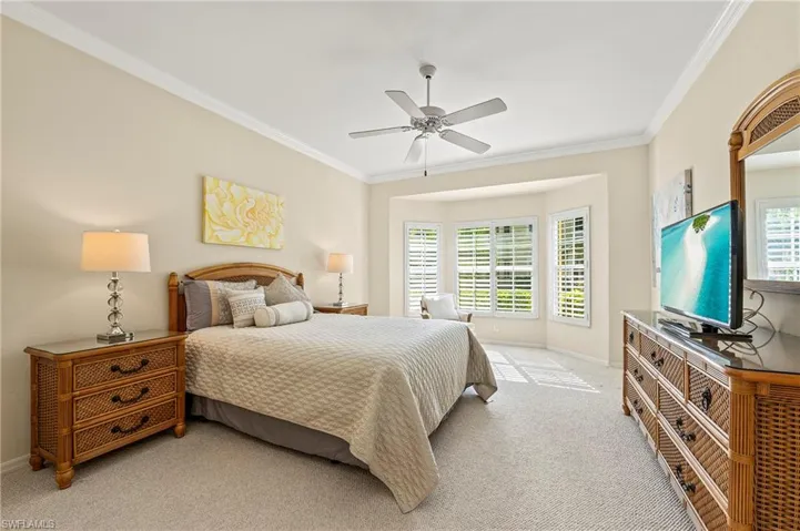 Bedroom with light colored carpet, multiple windows, and ceiling fan