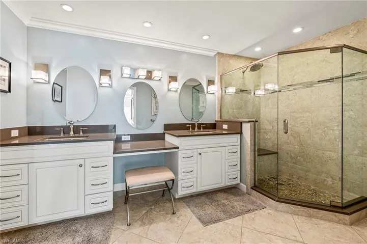 Bathroom featuring tile patterned flooring, vanity, ornamental molding, and a shower with door