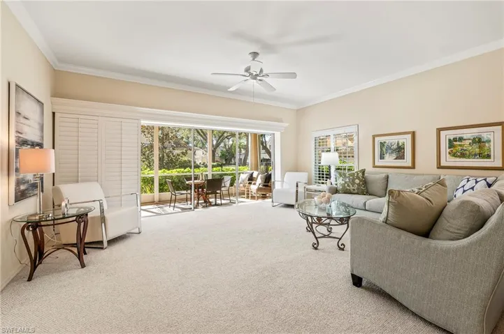 Carpeted living room with crown molding and ceiling fan