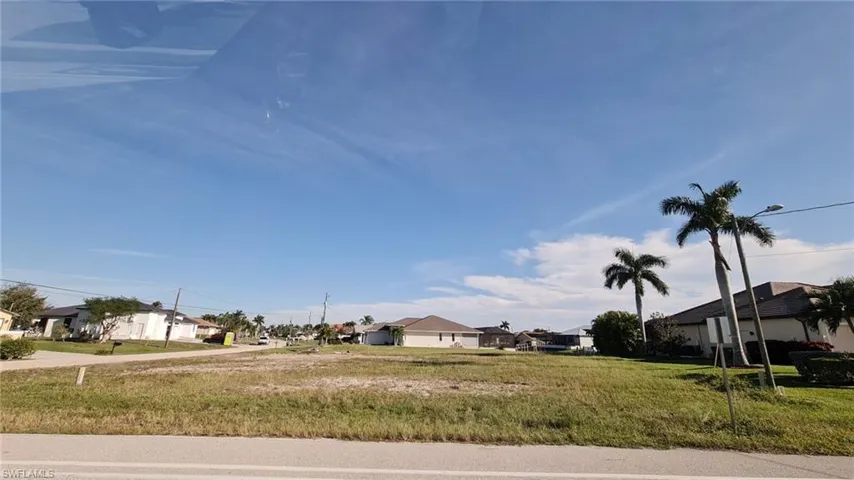 View of asphalt road featuring a residential view and street lights