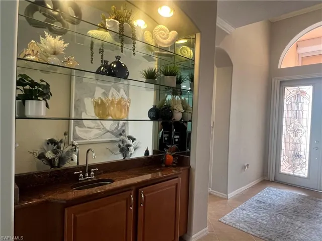 Bar with light tile patterned flooring, sink, and ornamental molding