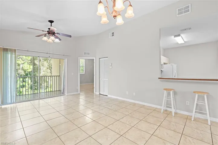 Unfurnished living room with a chandelier, light tile patterned floors, and a ceiling fan
