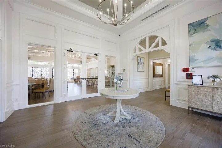 Bathroom featuring a decorative wall, suspended lighting, french doors, and crown molding