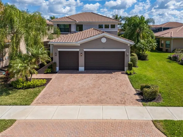 Mediterranean / spanish house with stucco siding, an attached garage, a front yard, decorative driveway, and a tile roof
