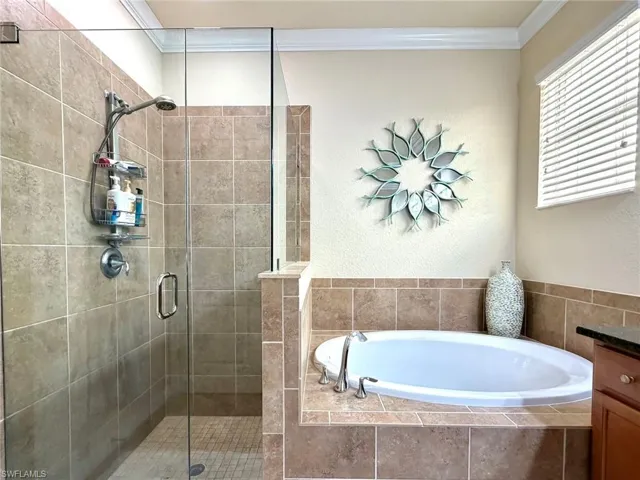 Full bath featuring a garden tub, a stall shower, crown molding, and vanity