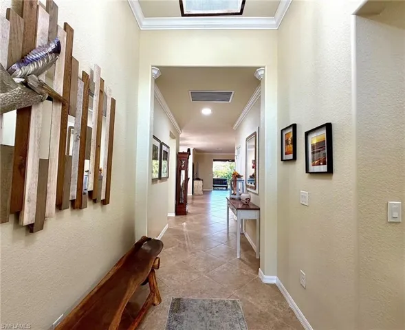 Corridor featuring a textured wall, ornamental molding, and light tile patterned flooring
