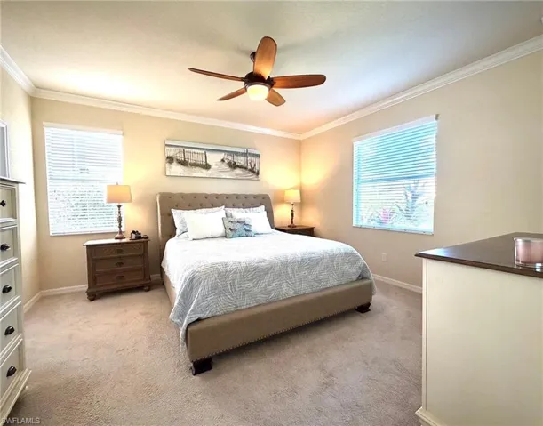 Carpeted bedroom featuring ornamental molding, a ceiling fan, and multiple windows