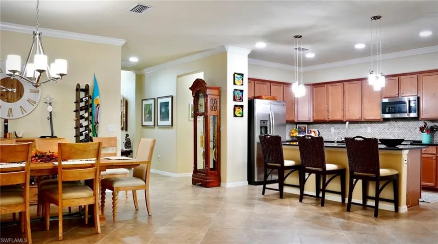 Kitchen with pendant lighting, a kitchen bar, brown cabinets, a kitchen island with sink, and stainless steel appliances