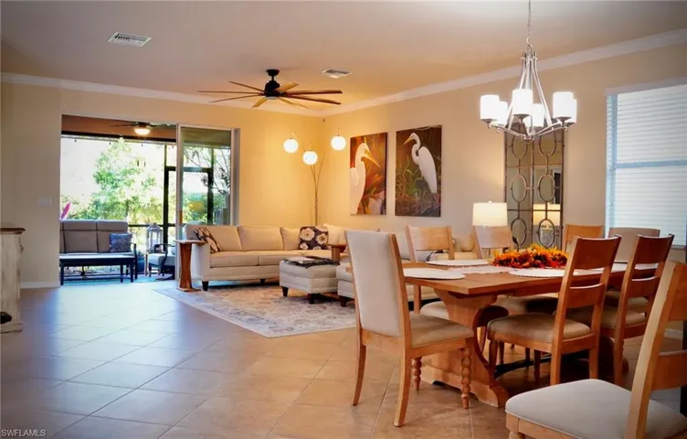Dining area featuring crown molding, a chandelier, light tile patterned floors, and a ceiling fan