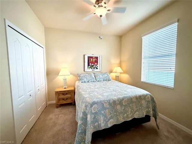 Carpeted bedroom featuring ceiling fan and a closet