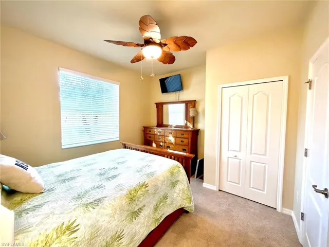 Bedroom with light carpet, ceiling fan, and a closet