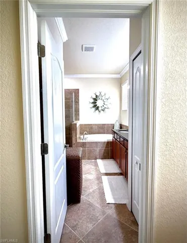 Bathroom with a bath, a textured wall, vanity, crown molding, and a textured ceiling