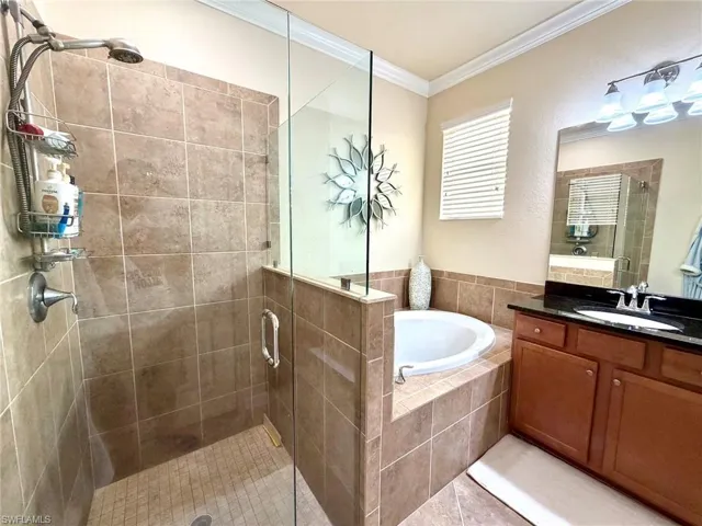 Bathroom with a stall shower, crown molding, a garden tub, vanity, and tile patterned floors