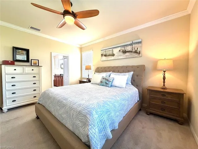 Bedroom with carpet, crown molding, ensuite bath, and a ceiling fan