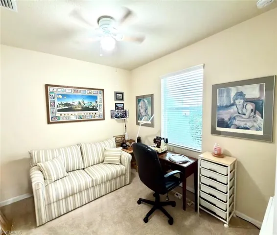 Carpeted home office featuring baseboards and a ceiling fan