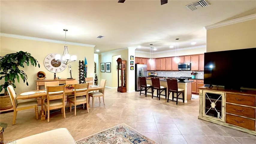 Dining room featuring crown molding, light tile patterned floors, ceiling fan, and a chandelier