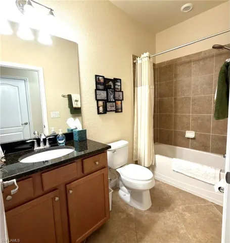 Bathroom featuring a textured wall, vanity, and shower / tub combo with curtain